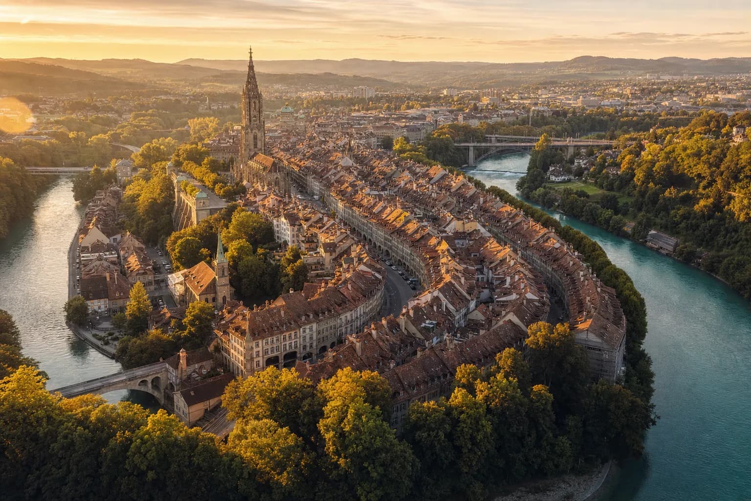 Die Berner Altstadt in der Aareschlaufe bei Sonnenuntergang, mit dem Münsterturm über den Sandsteindächern