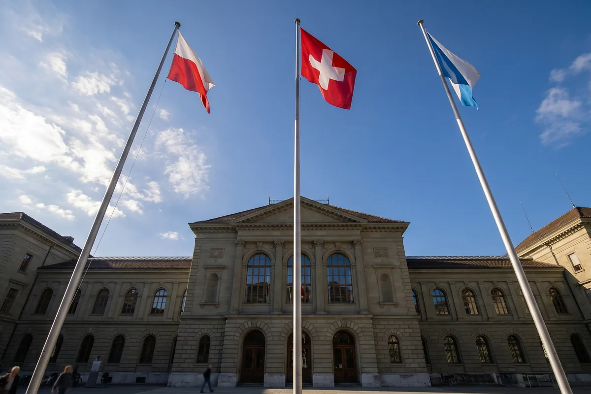 Drei Fahnenmasten mit der Schweizer Bundesflagge sowie Kantons- und Gemeindefahnen vor einem Regierungsgebäude als Symbol für die drei Ebenen des Schweizer Staates